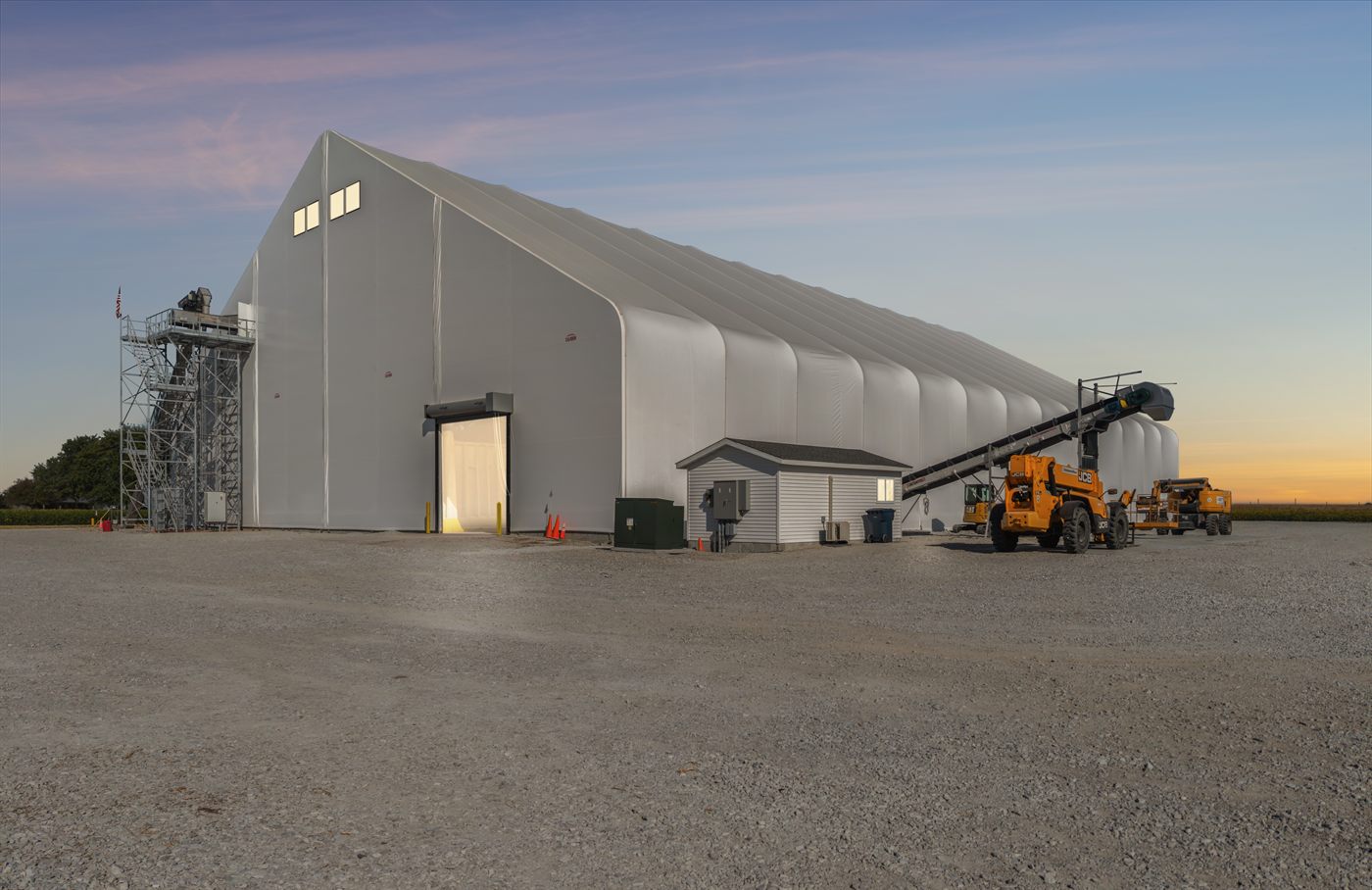 Calhoun fabric fertiliser storage building with loading equipment at dusk