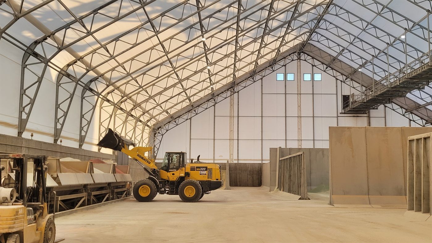 Wheel loader and bulk fertilizer piles inside a Calhoun fabric building