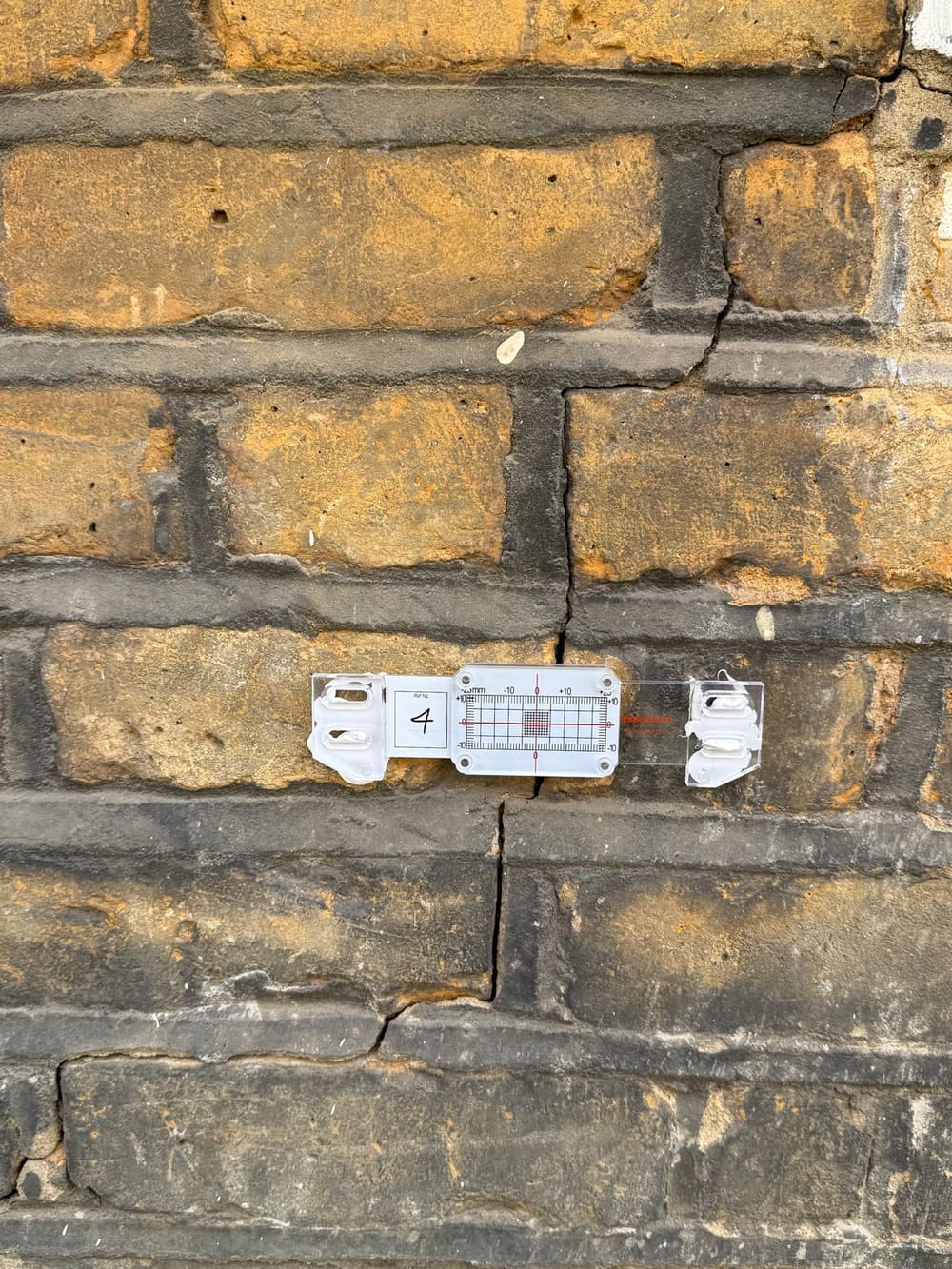 Crack monitor gauge fitted across a crack in London stock brickwork to assess structural movement before repair